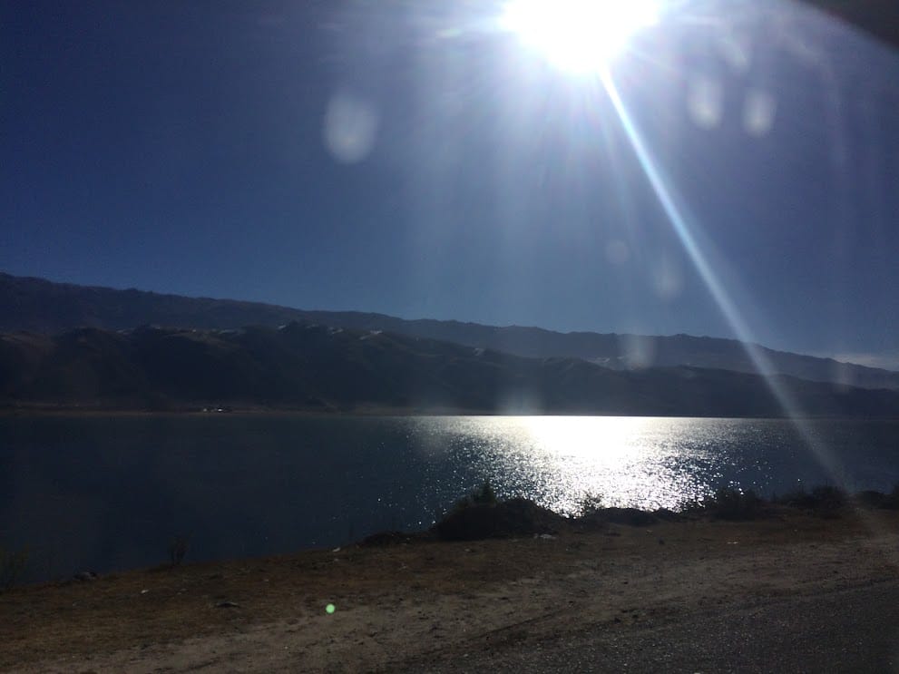 El sol reflejado sobre el agua del dique, a contraluz, desde el camino de la costa