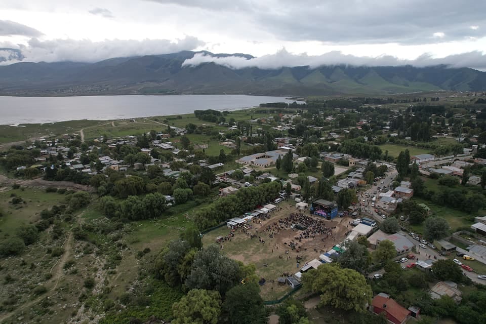 Vista aérea de la villa entre el dique y los cerros, con un escenario montado en un predio