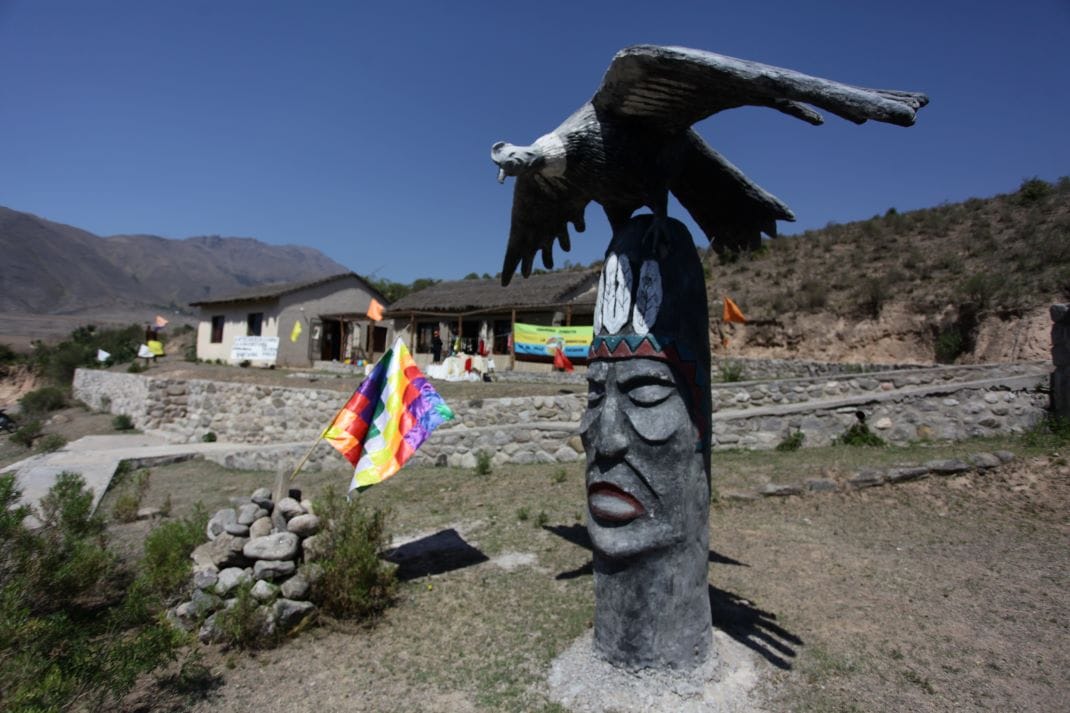 Una escultura de cóndor sobre un rostro tallado en piedra, frente al centro comunitario