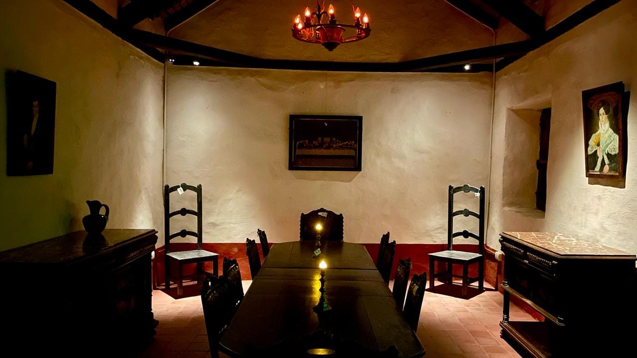 El comedor de época, con la mesa larga, las sillas de madera y los retratos en las paredes