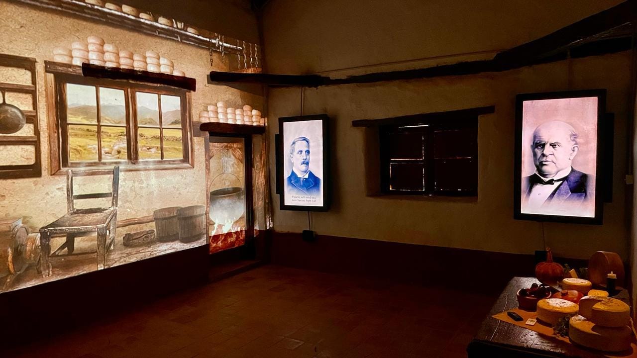 Una sala del museo con proyecciones sobre los muros de adobe y quesos sobre una mesa