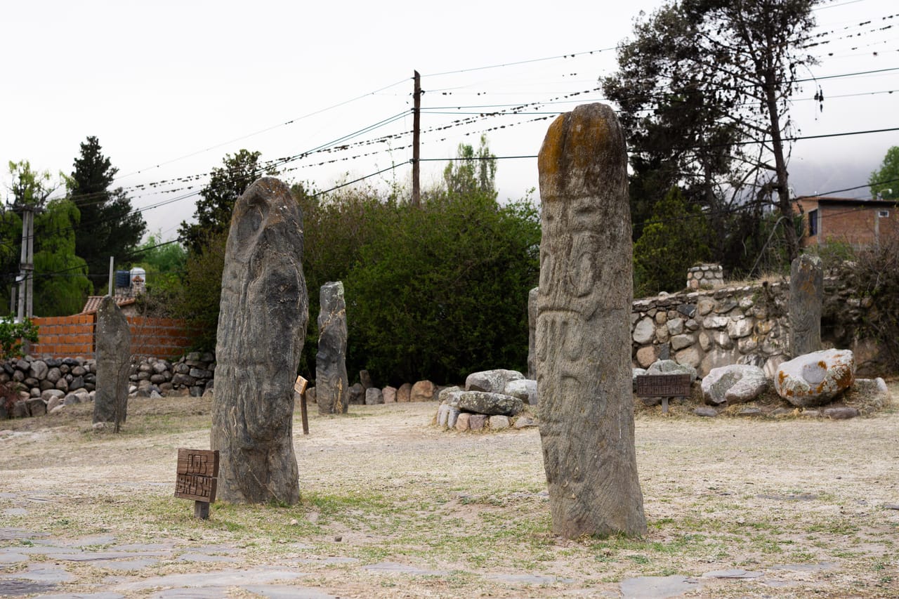 Dos menhires altos con figuras talladas, junto a los carteles que los nombran